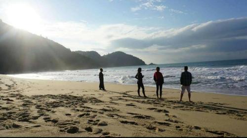 a group of people standing on the beach at Hostel Trópico de Capricórnio - Tenório in Ubatuba