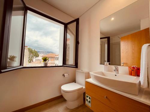 a bathroom with a sink and a toilet and a window at Living Funchal X in Funchal