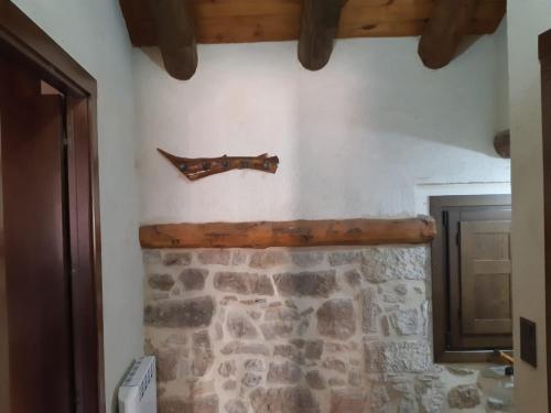 einen Steinkamin mit einem Holzpfeil an der Wand in der Unterkunft Casa Rural El Secreto del Castillo in Mora de Rubielos