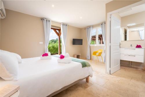 een slaapkamer met een groot wit bed en een gele stoel bij Villa Saint Corentin - 4 étoiles - Cap Est in Le François