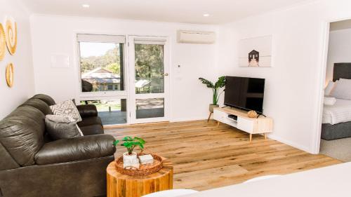 a living room with a leather couch and a television at McMillans of Metung Coastal Resort in Metung