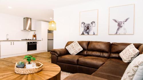a living room with a brown couch and a table at McMillans of Metung Coastal Resort in Metung