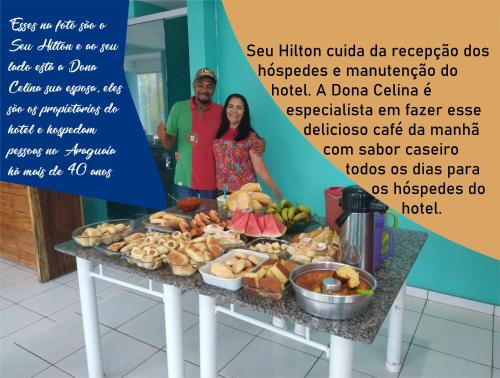 een man en een vrouw die naast een tafel met eten staan bij Hilton Hotel in Barra do Garças