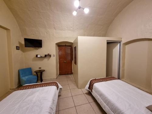 a room with two beds and a blue chair at Casona de Sillar in Arequipa