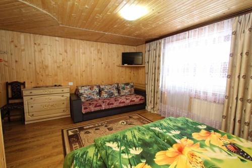 a bedroom with a bed and a window with a couch at Гостинний комплекс "У Валентини" in Yablunytsya