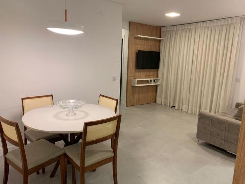 a room with a table and chairs and a living room at Apartamento 2 quartos home club na praia de palmas in Governador Celso Ramos