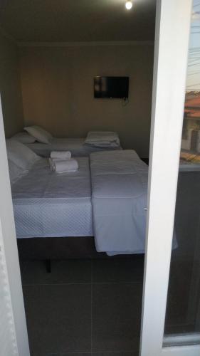 a bedroom with two beds and a tv on the wall at Hotel Kruger in Tramandaí