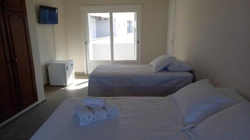 a room with two beds with towels on them at Hotel Kruger in Tramandaí