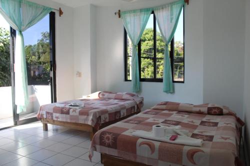 two beds in a room with two windows at Hotel Palmarito in Puerto Escondido