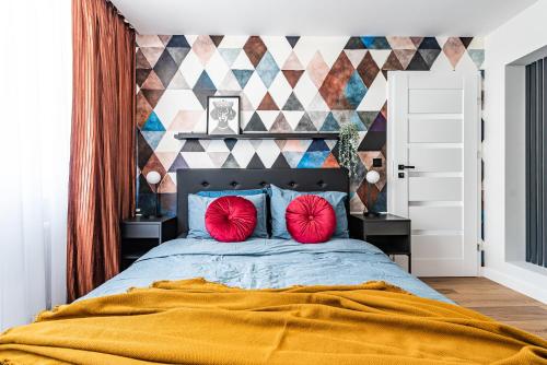 a bedroom with a large bed with two red pillows at Apartament Frida Katowice Ligota in Katowice