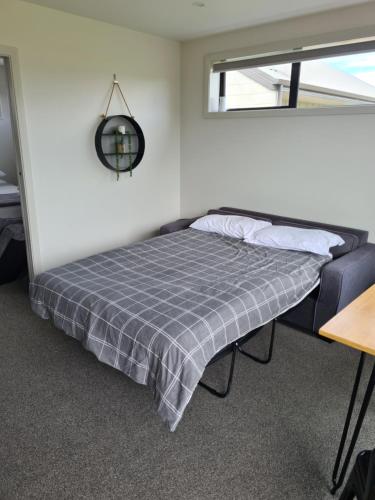uma cama com um cobertor xadrez cinzento num quarto em Two Thumbs Unit 1 em Lake Tekapo