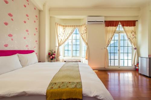 een slaapkamer met een groot bed en 2 ramen bij Ying Hsuan House in Hualien