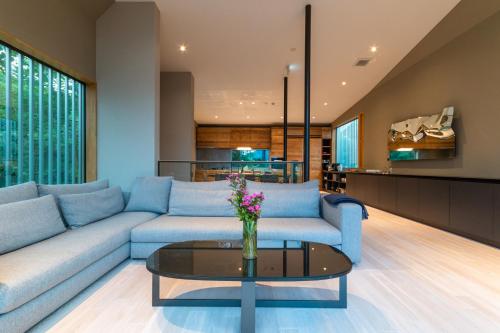 a living room with a blue couch and a glass table at Boheme by H2 Life in Kutchan