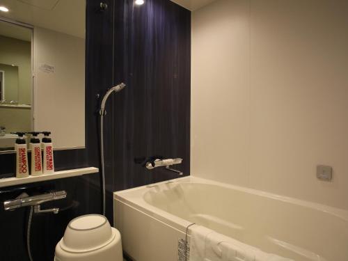 a bathroom with a bath tub and a toilet at Green Rich Hotel & Capsule Naha - Artificial hot spring Futamata Yunohana in Naha