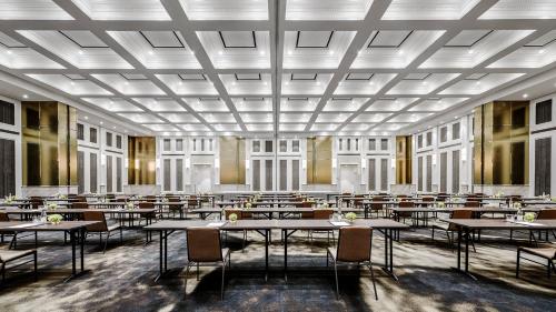 a dining room with tables and chairs and windows at The Langham, Jakarta in Jakarta