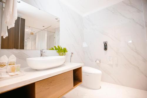 a white bathroom with a sink and a toilet at Songlam Waterfront Hotel in Hà Tĩnh