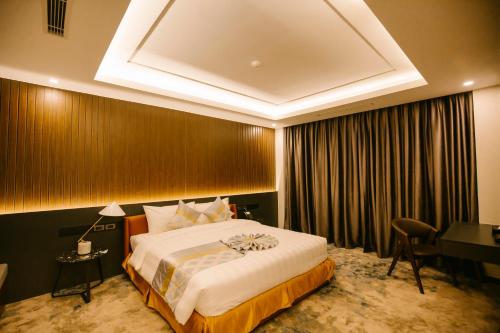 a hotel room with a large bed and a desk at Songlam Waterfront Hotel - 藍江酒店 in Ha Tinh
