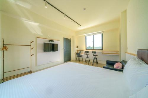 a bedroom with a large white bed and a tv at 太魯閣豐生活海館包棟民宿 T-aroko Fengst-ay Ocean Villa-------根據訂房人數提供相對的房間數量 Provide different number of rooms according to the number of people in the reservation in Shunan