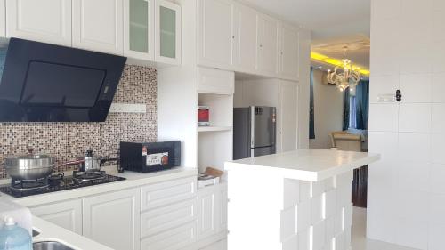 a kitchen with white cabinets and a tv on the wall at Lake Residence No73 - Classic Style, Cozy 1st Floor in Puchong