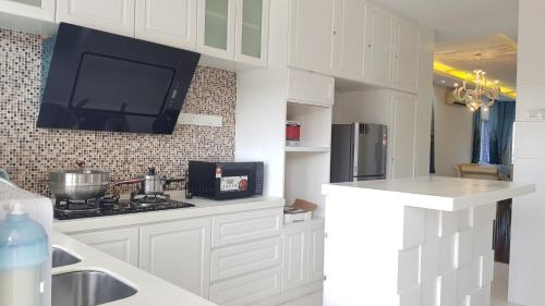 a kitchen with white cabinets and a tv on the wall at Lake Residence No73 - Classic Style, Cozy 1st Floor in Puchong