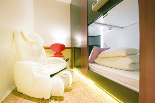 a room with a white chair next to a bed at Spa&Capsule Hotel Grandpark Inn Kitasenju in Tokyo