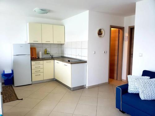 a kitchen with a white refrigerator and a blue couch at Apartment Blue - right at the beach in Ilovik