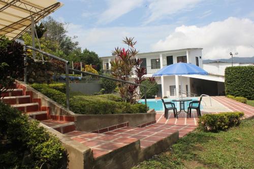 a house with a patio and a table with a blue umbrella at Quinta Baroe in Guaduas