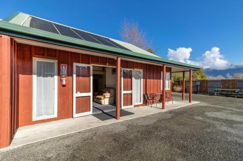 a house with a porch with a solar roof at Anatoki Lodge Motel in Takaka