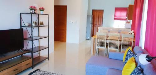 a living room with a tv and a living room with a couch at Новый дом 106 м2, территория 160 м2 и своя парковка in Phuket Town