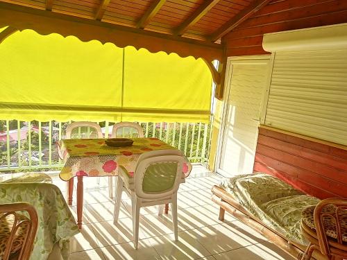 une chambre avec une table et des chaises sur une terrasse couverte dans l'établissement Souffle au paradis à Thomas Bouillante, à Bouillante