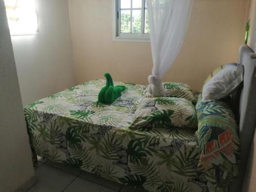 un canard jouet vert assis au-dessus d'un lit dans l'établissement Souffle au paradis à Thomas Bouillante, à Bouillante