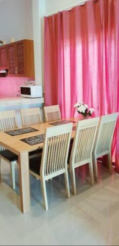 a dining room table with chairs and a pink curtain at Новый дом 106 м2, территория 160 м2 и своя парковка in Phuket Town