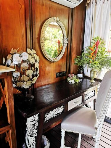 a room with a table with a mirror and chairs at Hôtel Fenua Mata'i'oa in Papetoai