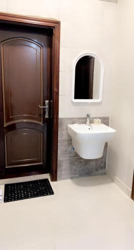 a bathroom with a sink and a door with a mirror at الشاطئ الأبيض للشقق المخدومة in Rayyis