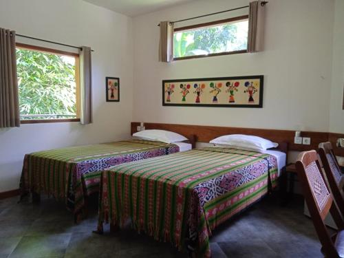 two beds in a room with two windows at The Country House in Senggigi 