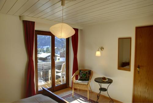 a bedroom with a bed and a chair and a window at Bergführer-Hüsle in Mittelberg