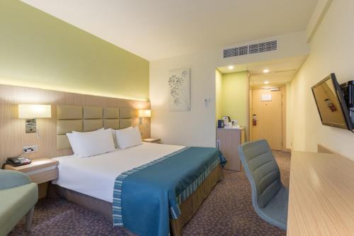 una habitación de hotel con una cama grande y una silla en Nesterov Plaza Hotel, en Ufa