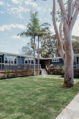 a house with two palm trees in the yard at Nelson Palms in Nelson Bay