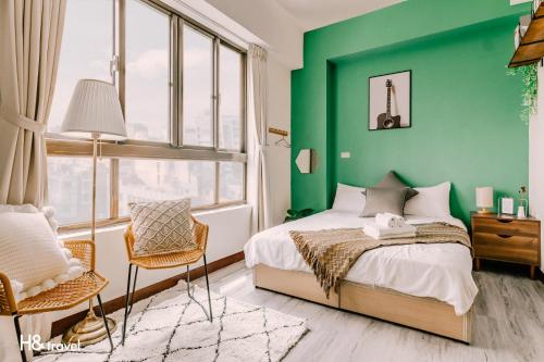 - une chambre verte avec un lit et une chaise dans l'établissement Tainan Haian Art Apartment, à Tainan