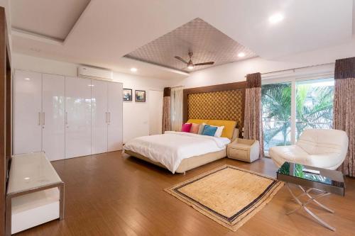 ein Schlafzimmer mit einem Bett, einem Stuhl und einem Tisch in der Unterkunft StayVista at Starry Deck with Pvt Pool & Terrace Access in Chennai