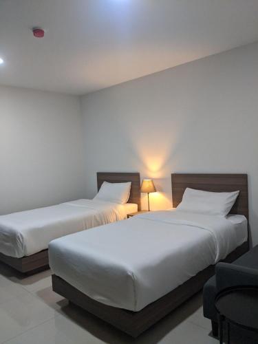 two beds in a room with white walls at Tassana Place in Chon Buri