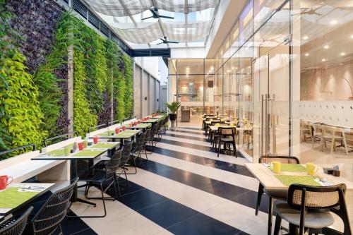 a restaurant with tables and chairs and plants at ibis Styles Bogor Pajajaran in Bogor