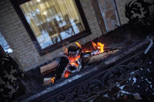 a fireplace with a fire in it next to a building at Kohavi Forest Club in Orlovshchina