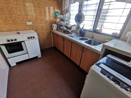 eine Küche mit einem weißen Herd und einer Spüle in der Unterkunft TRM Homestay Alor Setar - MALAY only in Alor Setar