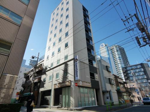 a tall white building on the corner of a street at Hotel Comfybed Ginza in Tokyo
