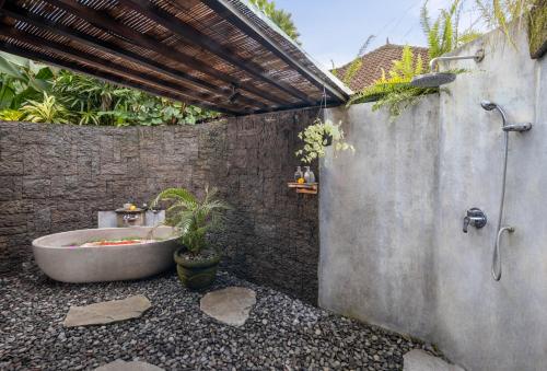 a bathroom with a bath tub sitting next to a wall at Madani Antique Villas in Ubud