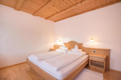 a bedroom with a bed with white sheets and pillows at App Lisüra Boè in Corvara in Badia