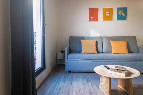 sala de estar con sofá azul y mesa en Modern Catalan Apartments by Olala Homes, en Hospitalet de Llobregat