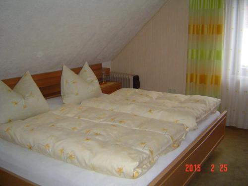 um quarto com uma cama com lençóis brancos e almofadas em Haus-Johanna em Riedlhütte