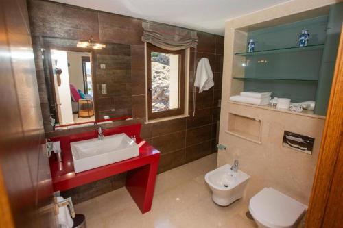 a bathroom with a red sink and a toilet at A Ballenera de Caneliñas in Cee